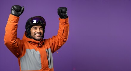 Happy young adult man in ski gear celebrating success with raised arms on a vibrant purple background, ready for winter sports.