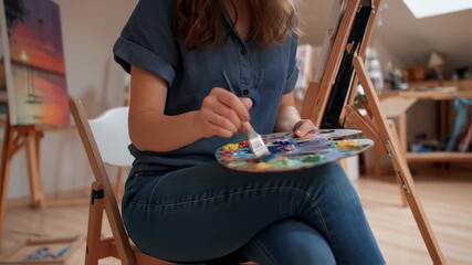 A young female artist passionately blends colors in her studio for her new artwork