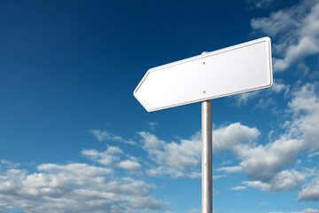 Blank, white hexagonal directional sign pointing left, mounted on a pole against a deep blue sky with bright white clouds.