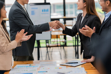 A team of successful Asian businesspeople shake hands and celebrate successful teamwork and goal achievement.