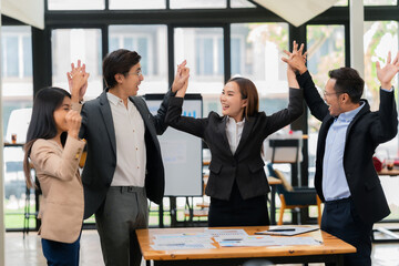 A team of successful Asian businesspeople shake hands and celebrate successful teamwork and goal achievement.