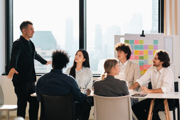 Professional business team having meeting discussing corporate strategy and project results using laptop in modern city environment showing teamwork leadership confident collaboration spirit