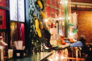 Naklejka premium Christmas market with illuminated food stalls, gift shops and kiosks, New Year outdoor fair decorations, garlands and festoons, Xmas atmosphere, retail and store illumination, decor in Europe city