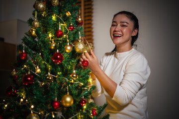woman decorating Christmas tree in home at night