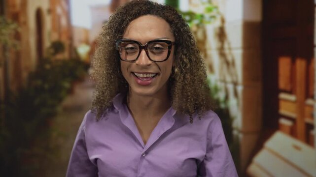 Hispanic transgender woman wearing glasses shows middle finger on sunlit old town street; bold defiance.