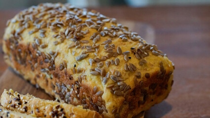 Warm macro of a seeded artisan bread loaf on a wooden board, showing detailed texture. Ideal for bakery menus, recipes, food blogs, and culinary branding