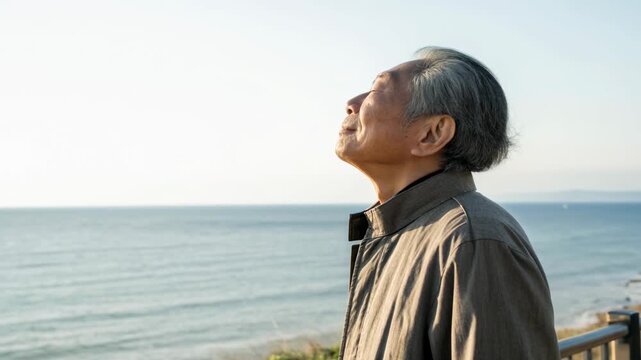 Elderly man standing by ocean enjoying peaceful sunlight elderly man relaxed by ocean enjoying sunlight and breeze, serene mood and peaceful