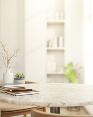 Pencil on book and pot plant on round marble table and wooden chair across bookshelf in living room.