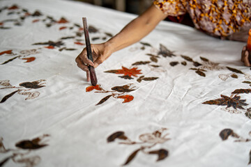 Batik Lukis - A batik artisan hand-paints colorful motifs onto fabric using a brush, enhancing traditional Indonesian batik patterns.