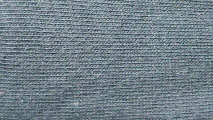 Intricate close-up of dark gray, hand-knitted textile showing the woven stitch pattern, ideal for warm fabric textures, backgrounds, and winter apparel designs.