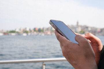 Person using smartphone by river in city