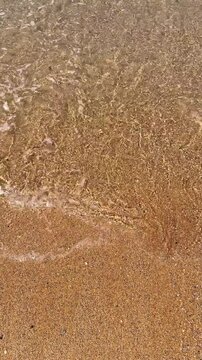 Calm waves gently lapping the shore on a sandy beach.