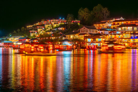 Night view of Thai ban with colorful lights reflecting on water near peaceful rak villag by hillside Ban Rak Thai village, Mae Hong Son, Thailand - Powered by Adobe
