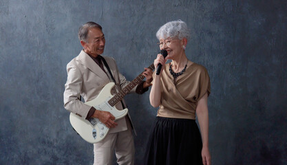 シニアのミュージシャン　男性のギタリストと女性のボーカル　黒背景