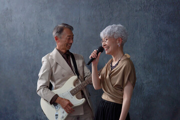 シニアのミュージシャン　男性のギタリストと女性のボーカル　黒背景