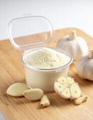 Garlic Powder and Fresh Garlic Bulbs on a Wooden Cutting Board.