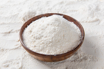 white flour in wooden bowl background.