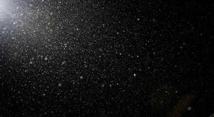 A snowfall against a black background with a bright light source.