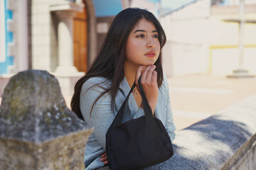 Young woman daydreaming in city, looking thoughtful