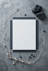 Minimalist flat lay composition with blank white paper and natural elements on a textured grey background