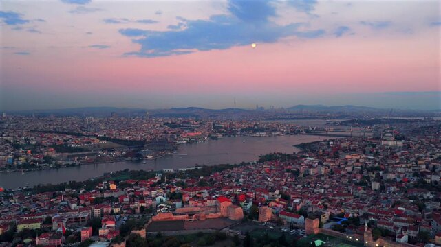 Istanbul Turkey T&uuml;rkiye cityscape aerial drone sunset pink sky afterglow buildings panoramic landscape skyscrapers Bosphorus Strait ferry boats harbor view Blue Horn Grand Bazar Mosque pan left