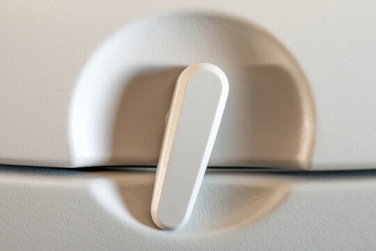Close-up view of a light gray airplane seat-back latch, highlighting its sleek and modern design, ideal for illustrating in-flight comfort
