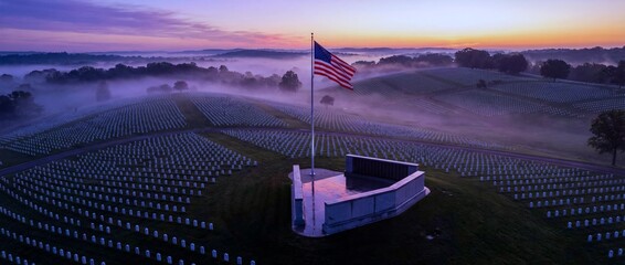 Morning light and fog over a cemetery with a flag