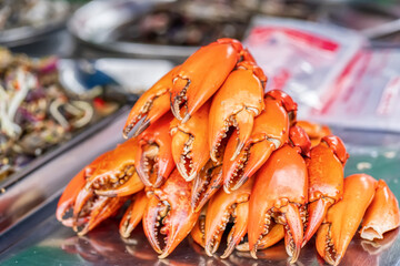 Pile of fresh steamed orange crab claws or paddle crab at seafood market stall.
