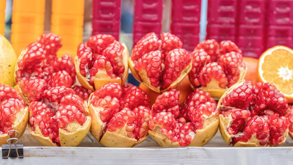 Fresh peeled pomegranate fruits showing bright red seeds displayed on a street food cart.