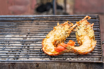 Grilled flathead lobster or slipper lobster topped with garlic on charcoal stove.