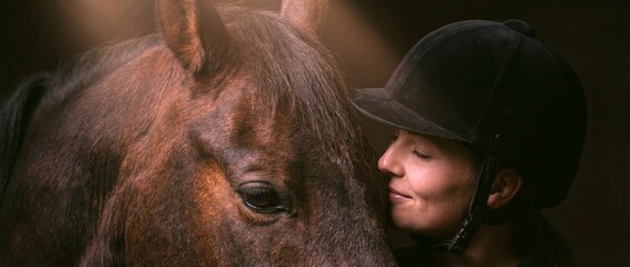 Woman interacts with horse in indoor stable setting during daytime