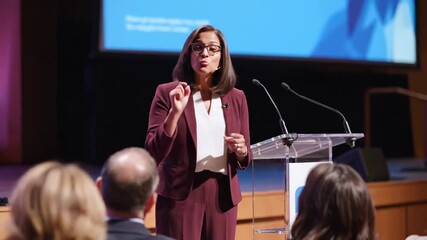 Professional Woman Giving Speech to Assembly - An academic professional delivers an enlightening speech from a clear podium to an attentive assembly.