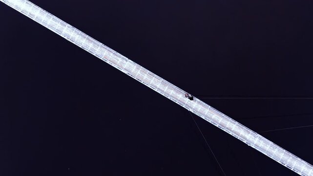 Two figures paused mid-bridge above flowing darkness in a tranquil still shot