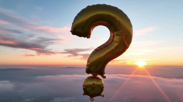 Golden Question Mark Balloon at Dawn - A large, gold-colored question mark balloon floats in the open air. The sky is a beautiful dawn scene, with soft pink and blue hues and a sea of clouds below.