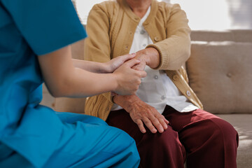 Nurse comforting a senior woman by gently holding her hands, symbolizing compassion, support, and...