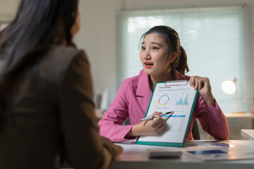 Confident businesswoman presenting monthly budget financial data, discussing strategy and analysis with a colleague in an office