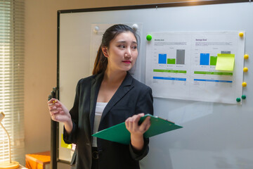 Young professional businesswoman presenting data and monthly financial goals from a clipboard in a modern office meeting