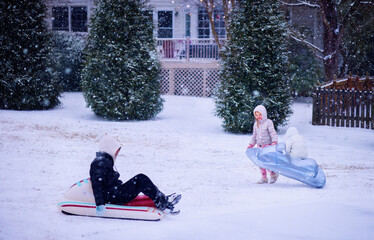 Children Sledding and Playing in a Snowy Backyard - Inflatable Sleds and Fun Winter Activity in Motion