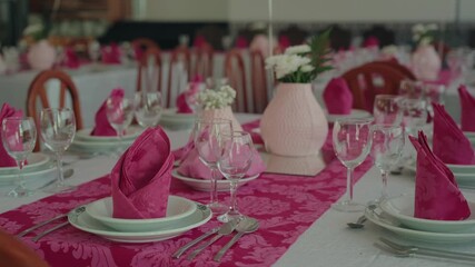Elegant pink themed table setup with folded napkins and glassware for celebration