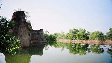scenic view of tall rock formations reflecting in calm green water under clear sky located in nature park popular among travelers for peaceful retirement exploration and outdoor enjoyment