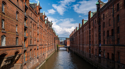 Brick warehouses along canal Waterway through historic district Industrial architecture in Hamburg Urban travel landmark European heritage view