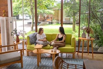 Two Asian women relaxing and chatting in a bright cozy living room