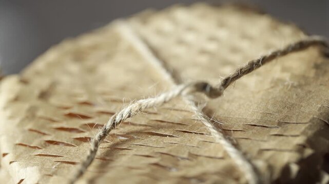 Woman opens gift with brown wrapping and string