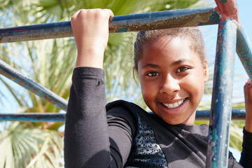 Fototapeta premium African child, smile and play at playground for fun, adventure and holiday with bars for growth. Kid, portrait and black girl at park for exploration, development and vacation outdoor in Namibia