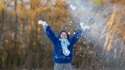 Happy kid throwing snow. Child playing in winter snow. Winter fun with children. Winter kid play...