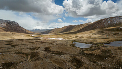 Aerial view over Bartang Valley in Tajikistan, showcasing rugged Pamir‑mountains terrain, a winding river, steep valleys and remote mountain villages