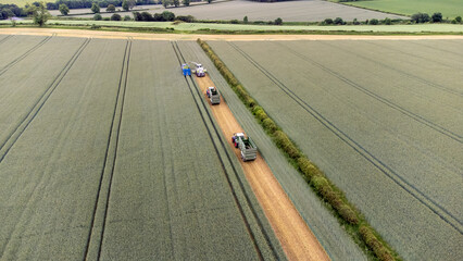 Aerial view of working farm vehicles harvesting a field