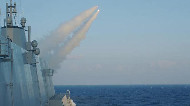 Warship attacks in the open seas by firing a few missiles. Frigate fires rockets in the ocean