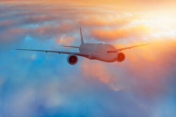 White passenger airplane flying in the sky amazing sunset clouds in the background - Travel by air transport