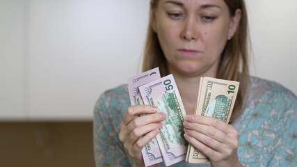 A housewife sits at her kitchen table counting cash for daily expenses. She focuses intently on her notes, making sure her budget is precise for her family's needs.